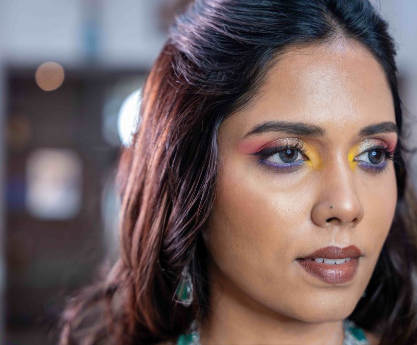 Woman with colorful eye makeup and a glowing skin finish after a simple makeover at Lara Styles Salon.